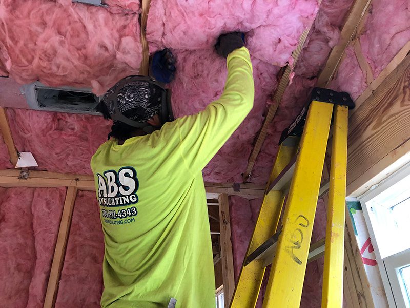 An insulation contractor installing fiberglass insulation for a commercial insulation project
