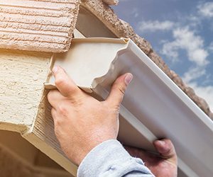 A gutter installer adding k-style gutters to a home